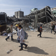 Children walk past rubble of destroyed buildings