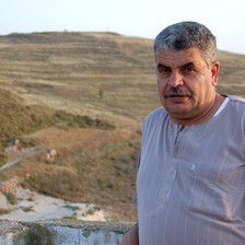 Man stands with Israeli outpost on hill in background