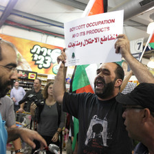 Man holds up sign reading "Boycott occupation and its products" in Arabic and English