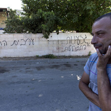 Men stand near wall sprayed-painted with graffiti