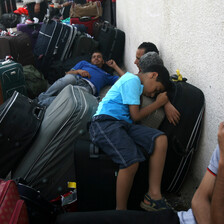 Men and boys sleep on suitcases