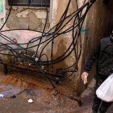 Youth walks in narrow alleyway where lots of electrical cables hang