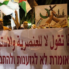 Men carry banner reading Yaffa says no to racism and settlements in Arabic and Hebrew