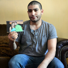 Man sitting on couch holds photo of him and young woman embracing