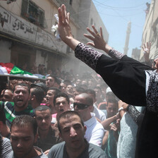 Woman raises her hands above passing funeral procession