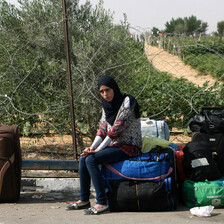 Young woman looks unhappy as she sits outdoors among suitcases