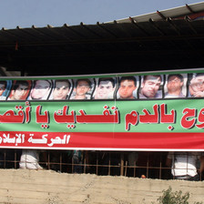 Arabic-language banner features the portraits of 13 males shot by Israeli police