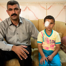 Man sits next to boy wearing cotton bandage eye patch