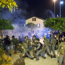 Riot gear police wearing army type uniforms chase demonstrators