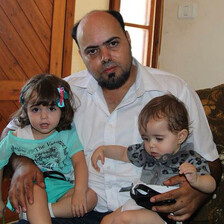 Photo shows Amjad Safadi sitting on couch holding two small girls