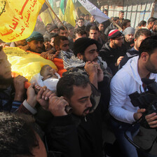 Men carry body of young man wrapped in yellow flag