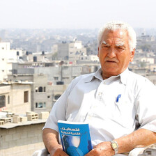 Elderly man sits on rooftop while holding book