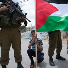 Photo shows boy holding Palestine flag crouching between Israeli soldiers