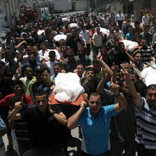 Crowd of men carry shrouded bodies during funeral procession