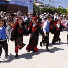 Boys and girls hold hands while performing a line dance