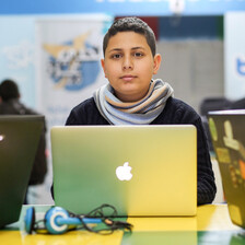 Boy sits at table with a laptop in front of him