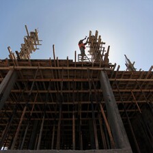 Man hammers on top of partially-constructed building