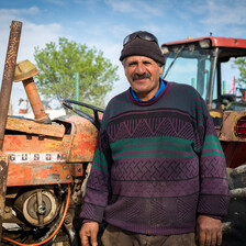 Smiling middle-aged man stands in front of farming equipment