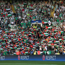 Dozens of football spectators hold up Palestinian flags in full stadium