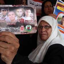 Woman in headscarf holds photo showing four men abducted in Egypt