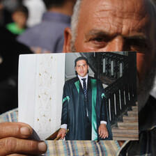 Older man holds photograph of young man wearing graduation gown