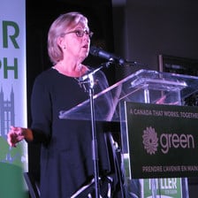 Green Party leader Elizabeth May speaks into microphone at podium