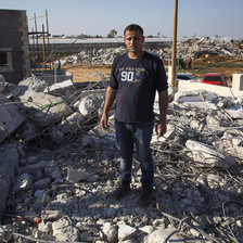 Young man stands on rubble of demolished home