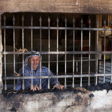 Man stands behind barred window in burned-out room