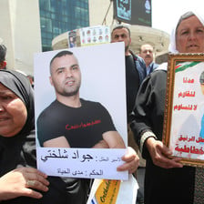 Women hold posters showing photos of men detained by Israel