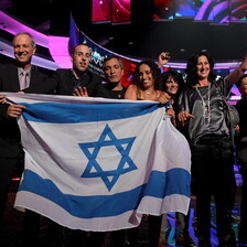 Group of people on Eurovision stage hold Israeli flag