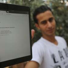 Young man holds up electronic tablet showing an Internet browser error stating, There is no Internet connection