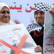 Elderly women hold up posters protesting the Balfour declaration