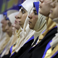 Photo shows row of young women wearing headscarves and graduation robes