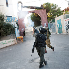 Photo shows soldiers firing tear gas in front of gate to Aida camp that has a giant key on top of it