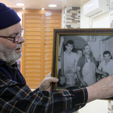 Man in wool hat looks at framed photo he is holding up