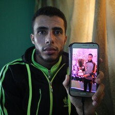 Young man in athletic wear holds up phone showing him receiving a trophy