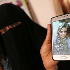 Woman wearing niqab displays photo of adolescent girl wearing a hijab on a mobile phone