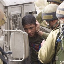 A group of Israeli soldiers put a boy wearing a Spiderman T-shirt into a military jeep