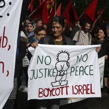 A woman holds a banner reading No Justice No Peace Boycott Israel amid crowd