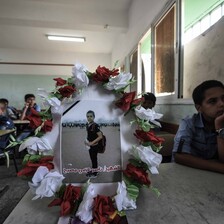 Wreathed photo of boy standing at protest sits on desk in a schoolroom with boys sitting at the desks