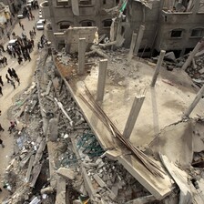 Birds-eye-view of people standing next to the rubble of a mosque