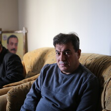 Man sitting on couch facing camera is seen from waist up