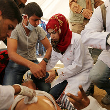 Medics treat wounded person lying on ground