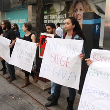 About six people stand with signs calling to end Israeli violence against Palestinians