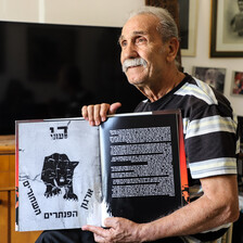 Man sits while holding a book open