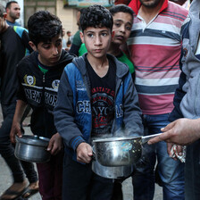 A man's hand can be seen holding a pot, behind him a boy holds a similar container.