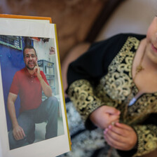 Girl looks at photo of smiling man in album