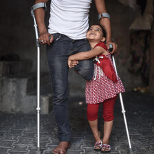 Girl hugs man using crutches seen from chest down