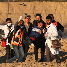 Six people, including medics, carry a man wounded in a protest.