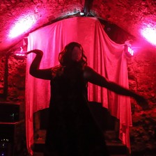 A dark silhouette against a red curtain of a person dancing